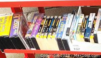 VHS tapes, books, CDs and DVDs organized on red shelves