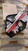 Top-down photo showing seven red-framed canvases packed vertically inside a black tote bag.