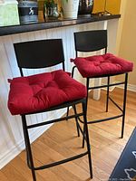 Two black bar stools with red cushions placed at kitchen counter, showing overall structure and seating area