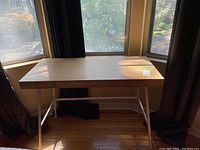 Front view of the wood grain desk with metal frame and angled legs.