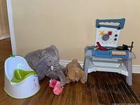 Photo showing child's toy workbench, three stuffed animals (elephant, dog, pink), and child's potty