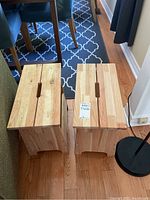 Two wooden side tables placed side by side on a hardwood floor with natural wood finish and visible screw joins.