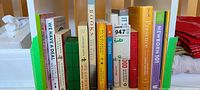 Photo shows a mix of hardcover and softcover books standing upright on a shelf. Titles and authors visible on many, including Sapiens and Homo Deus by Yuval Noah Harari.