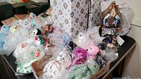 Photo of assorted TY Beanie Babies plush toys wrapped in plastic bags in front and ceramic pieces in the back on a table.