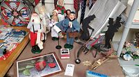 Full view of Byer's Choice caroler figures including Santa, mailman, children, Christmas Ghost with Dickens silhouette candle holders and decorative brass sun ornament