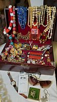 Full view of costume jewelry including necklaces, pins, watches, eyewear, and jewelry box.