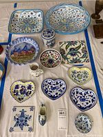 Full top view of 14 ceramic pieces showing bowls, jars, plates, dishes, and tiles arranged on white surface.