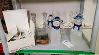 Spode Christmas Tree mugs in original box with visible Christmas tree design, two crystal candle holders, two glass snowmen luminaries with blue accents, three Lenox wine glasses, and a Christmas Angel keepsake box.