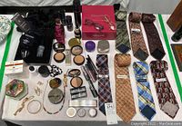 Full lot overview of skin care, makeup, ties, and jewelry items arranged on table