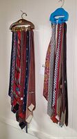 Men's neck ties hanging on wooden and plastic tie racks, showing a variety of colors and patterns.
