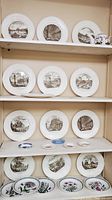 Four shelves displaying twelve Wedgwood Piranesi plates with monochrome architectural images and various smaller plates below