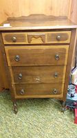 Front view of antique wooden dresser with four drawers, decorative backboard, and metal ring pulls