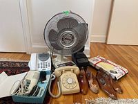 Various items on floor including rotary phone, cordless phone, fan, hair dryer, wooden shoe trees