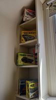 Five vintage model car kit boxes stacked on narrow shelf near window showing 1971 T-Bird, 1969 Cougar, Big Bird Firebird, and others