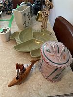 Photo showing sectional serving tray, covered ceramic container, wood whale with picks, rectangular planter and toothbrush holder on marble table surface.