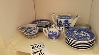 Full display of tea set showing cups, saucers, plates, teapot, and sugar bowl on shelf
