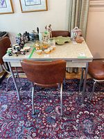 Vintage table and four chairs set from front angle showing table surface and chair upholstery