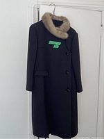 Front view of dark women's coat with mink fur collar hanging on a hanger
