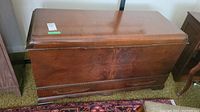 Front view of vintage solid wood cedar chest with closed lid and lower drawer visible.