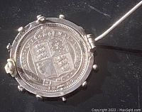 Close-up of the brooch front showing the 1887 one shilling coin reverse with coat of arms detail.