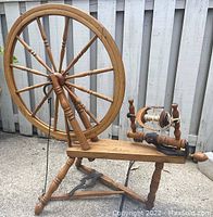 Full view of the spinning wheel showing the drive wheel, treadle, and base structure.