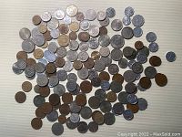 Top-down image showing a large assortment of over 140 primarily Asian coins laid out loosely on a flat surface, in various sizes and metal finishes including copper, bronze, silver-tone.