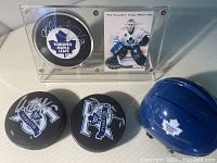 Mini helmet signed by Ron Ellis, accompanied by three autographed pucks and one trading card inside a protective display case.