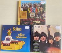 Front view of the three sealed Beatles DVDs showing the cover artwork.