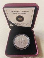 Canadian 2011 ten-dollar silver coin shown inside burgundy Royal Canadian Mint presentation box with certificate inside lid.