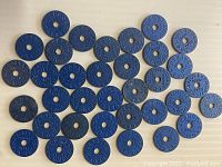 Twenty-five blue circular World War Two Canadian meat ration tokens arranged in rows on a flat surface.