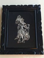 Full view of framed filigree artwork showing the black carved wooden frame and silver thread filigree on black background