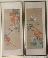 Pair of two framed oriental watercolour paintings depicting birds and flowers on beige paper, showing entire artworks and framing.
