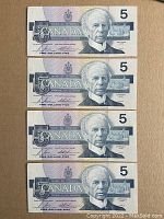 Front view of four 1986 Canadian five-dollar banknotes featuring Sir Wilfrid Laurier, arranged vertically.