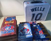 Photo showing multiple Oh Henry Toronto Blue Jays baseball card boxes from 1997, 1998 and 1999 with a metal lunch box behind.