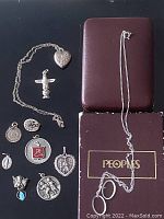 Overall view of two sterling silver chains, one in original People's box, and nine sterling silver pendants arranged for display.