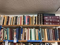 Two shelves filled with books, a mix of hardbacks and paperbacks, showcasing diverse titles and colors