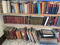 Photo showing three shelves filled with books in varying sizes and bindings, arranged with hardbacks and paperbacks including vintage editions and series sets.