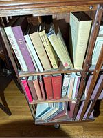 Books arranged on a three-tier wooden rotating bookcase, showing titles related to Harvard University, with mix of hardcovers and paperbacks.