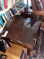 Top view with leaves partially folded out revealing oval shape and metal hinges.