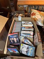 Photo of a box filled with DVDs including The Daily Show, Jack Benny, MacGyver, and more