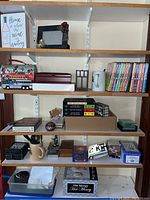 Full view of shelving unit showing an assortment of items including DVDs, figurines, boxes, and decorative plaques.