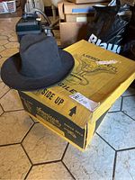 Black American Hat Co wide brim hat on original yellow branded box with eagle design.