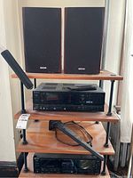 Front view of stereo cassette deck, remote control on top, two speakers on shelf