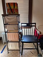 Photo showing tall storage unit with four cloth bins and wooden arm chair side by side.