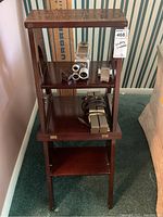 Full view of wooden folding ladder with some items placed on steps for scale.