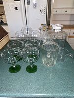 Set of glassware on countertop including glasses, jug, measuring cup, and container