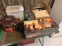 Variety of glassware including boxed 18-piece hi-ball glass set, assorted green and clear drinking glasses, and Coca-Cola glassware box.