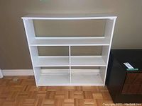 Front view of white wooden shelving unit showing its open shelving compartments.