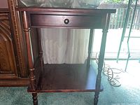 Full front view of wooden side table showing drawer and lower shelf