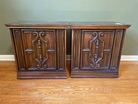 Pair of wooden side tables placed side by side showing ornate carved front detailing and dark brown finish.